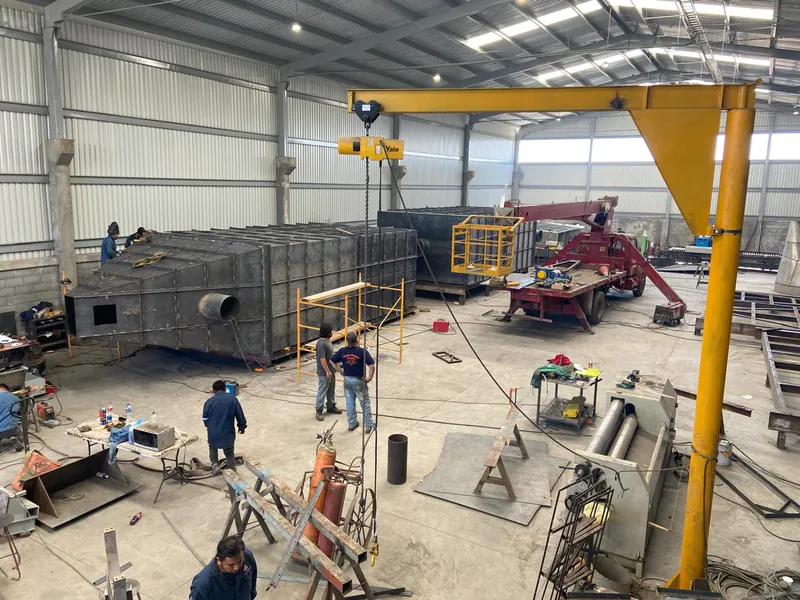 Nave de PSI 24-7 con dos cámaras de colector en armado, grúa pluma y la cuadrilla trabajando.